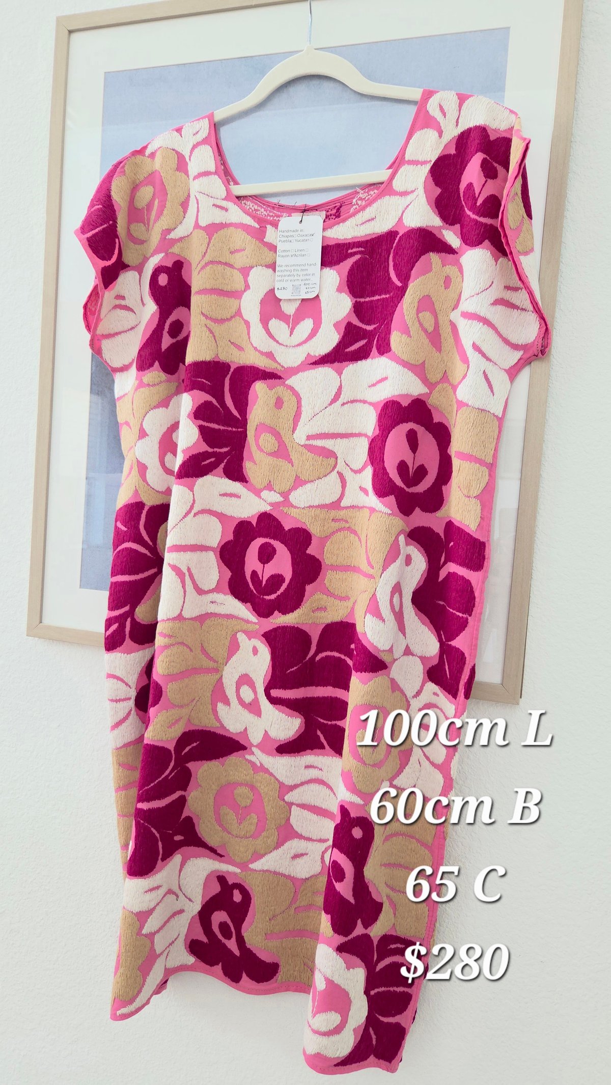 Vestido floral rosa con flores vino y beige en percha dentro de marco de madera